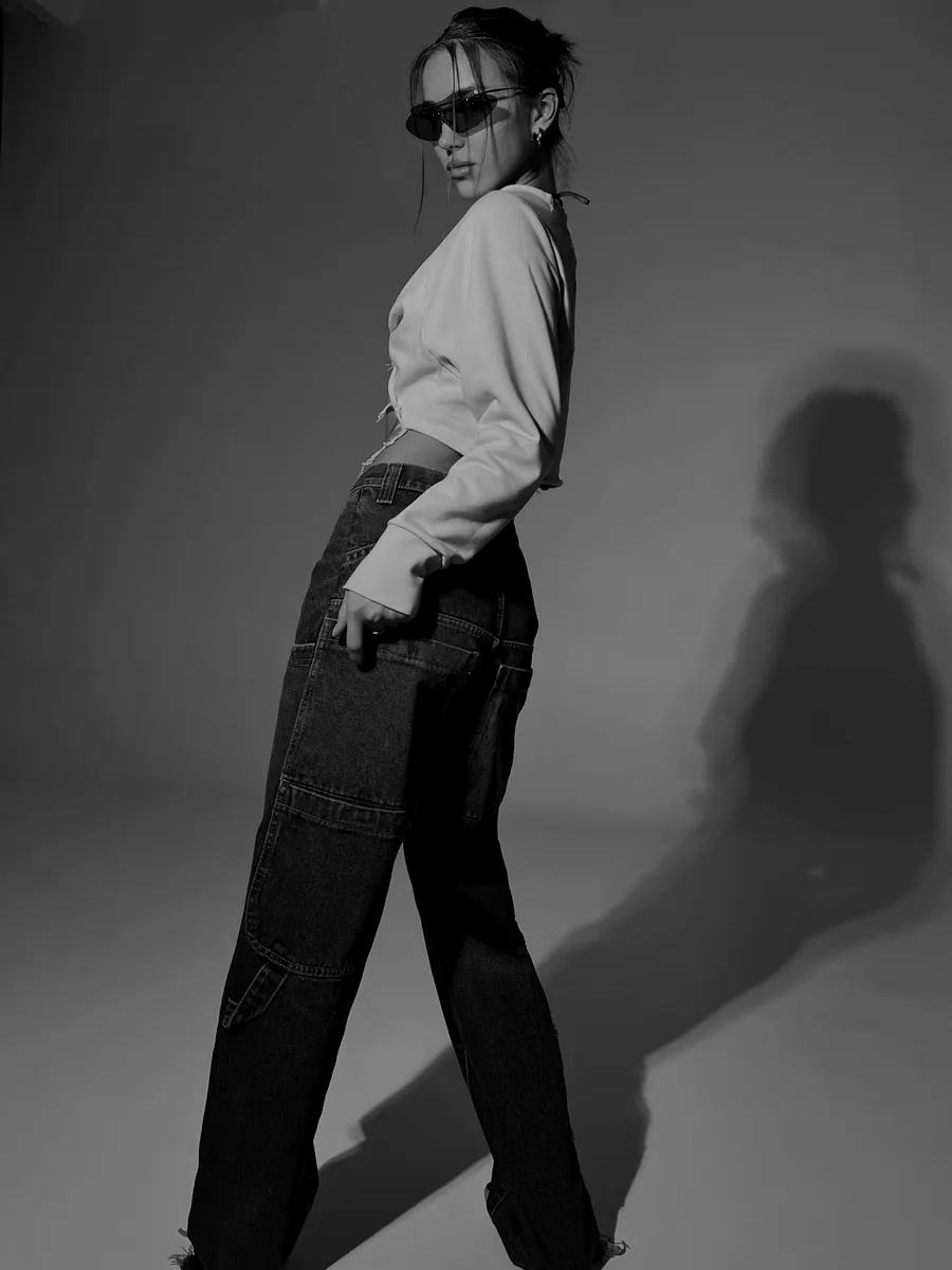 Mujer con pantalón baggy oscuro y anteojos de sol